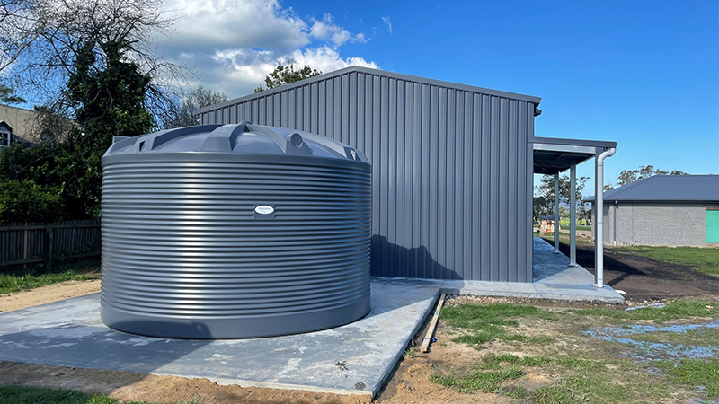 A 31,700L Polymaster Blue Water Tank installed beside a shed under a clear blue sky