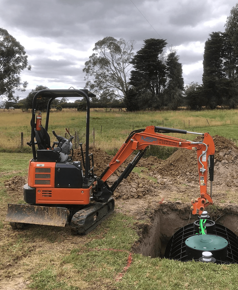 A mini tractor lifting and installing Polymaster septic tank on a hole