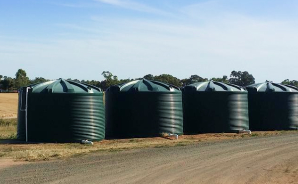 four green Polymaster water tanks insitu on a field