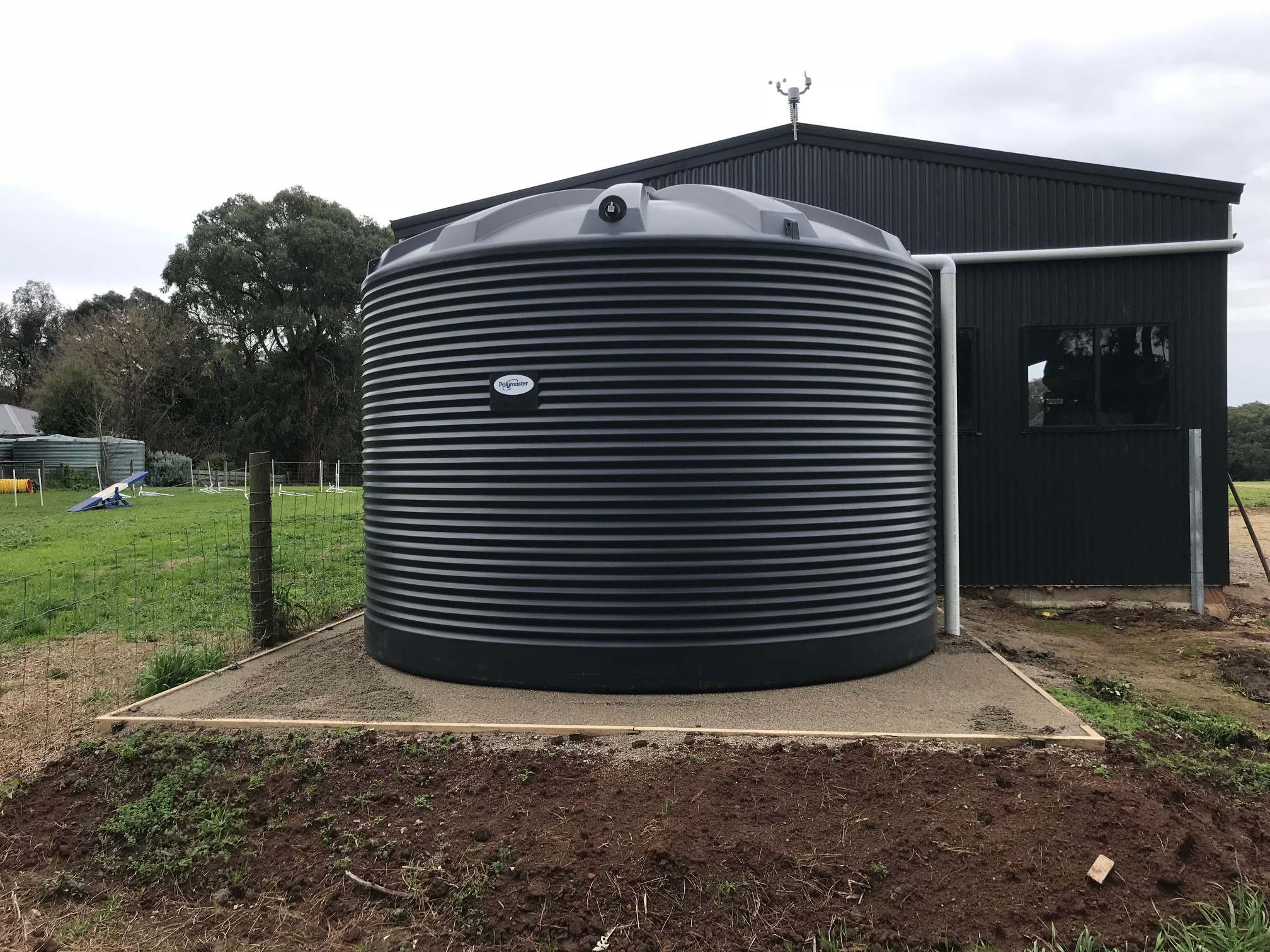 Polymaster black/jasper corrugated water tank installed beside a shed